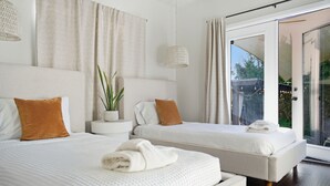 Ein modernes Schlafzimmer mit zwei Betten, einem Blumentopf und einem großen Fenster.