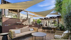 Ein Terrassenbereich im Freien mit einer Couch, einem runden Tisch und Korbstühlen.