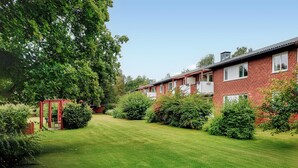 A row of red brick houses with white window frames, surrounded by well-maintained lawns and dense greenery. - 2 bedroom nice apartment in Hyltebruk (Hyltebruk)