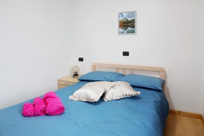 Una cama con ropa de cama azul, un cabecero de madera y dos almohadas.