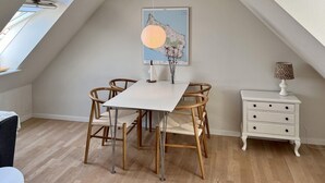 A dining area with a white table and four wicker chairs, a white nightstand with drawers, and a map on the wall. - Amazing apartment in Gudhjem with WiFi (Gudhjem)