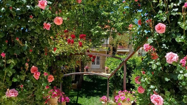 A garden pathway surrounded by lush pink roses, leading to a stone archway. - Laklouk 1808 lodge by Hansa (Laklouk)