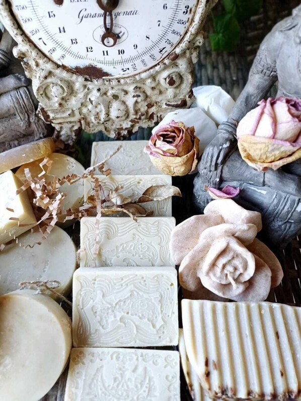 A vintage scale, various soaps, and a statue of a hand holding a rose.