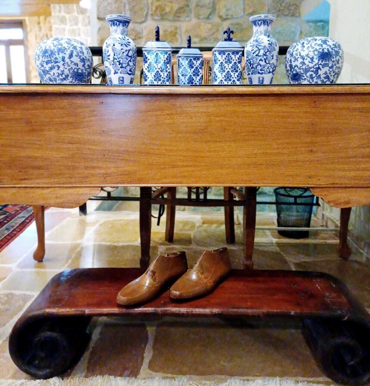 Una mesa de madera con un par de zapatos marrones sobre un pequeño carro de madera debajo.