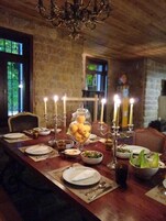 Una mesa de comedor dispuesta con platos, cubiertos, velas y un centro de mesa de limones.
