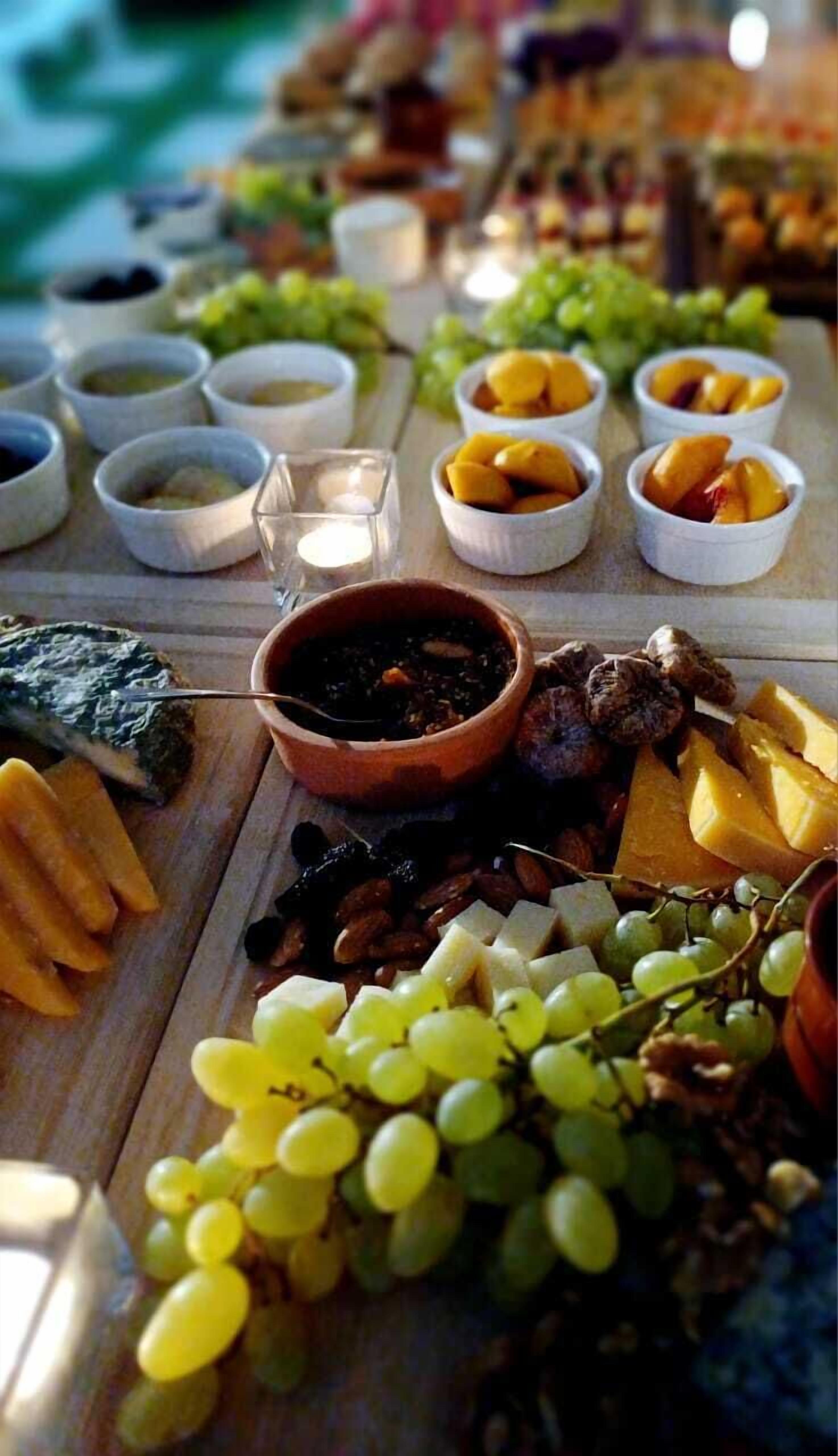 A table with various food items including grapes, cheese, and fruits, suggesting a buffet or picnic setting.
