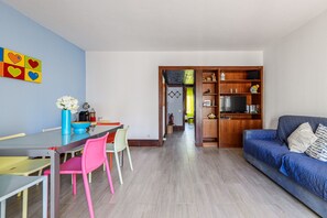 Un salon moderne comprenant un coin repas, un canapé et un meuble pour la télévision.