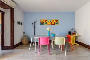 Un coin repas comprenant une table, des chaises, un vase avec des fleurs, une œuvre d’art murale et une lampe.