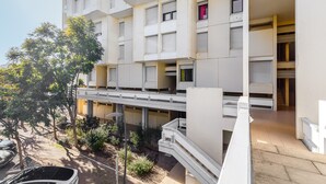 Un immeuble résidentiel à plusieurs étages, doté de balcons, d’un espace extérieur couvert et d’un escalier.