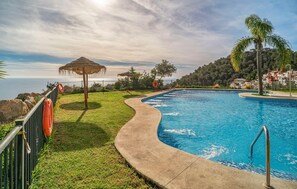 A swimming pool with a curved edge, surrounded by a concrete deck, a grassy area, and a fence. - 4 bedroom gorgeous home in Almuñecar (Almuñecar)