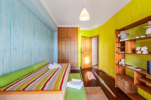 A bedroom with a bed, a wooden wardrobe, a shelf with decorative items, and a hallway. - Apartment 'Setúbal Dreams' with Sea View, Private Garden and Wi-Fi (Setúbal)