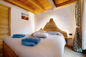 A wooden-framed bed with a white headboard, blue towels, and a small bedside table with a lamp.