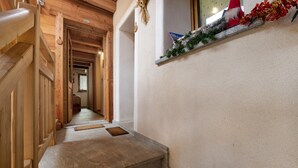 Een houten trap die leidt naar een kamer met een witte muur en een plank met vakantieversiering.