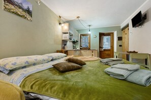 Une chambre d’hôtel avec un lit, des oreillers, une couverture verte, un four à micro-ondes, un lavabo et un téléviseur.