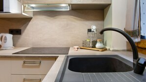 Een moderne keuken met een zwarte spoelbak, een magnetron en een waterkoker op het aanrecht.