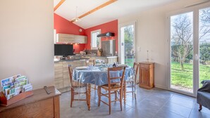 A modern kitchen with a dining area, wooden beams, and a view of the outdoors.