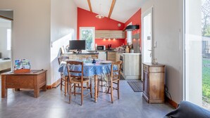 A modern kitchen with red walls, wooden beams, and a dining area with a table and chairs.