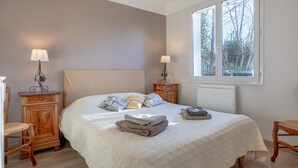 A bedroom with a bed, two bedside tables, a window, and a radiator.