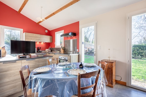 A modern kitchen with red walls, a dining area with a table set for four, and a large window providing a view of the outdoors.
