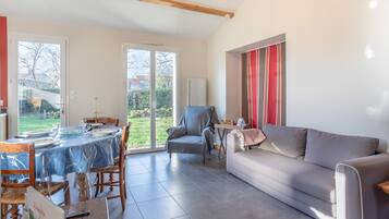 Een ruime woonkamer met een eettafel, een bank en een stoel.