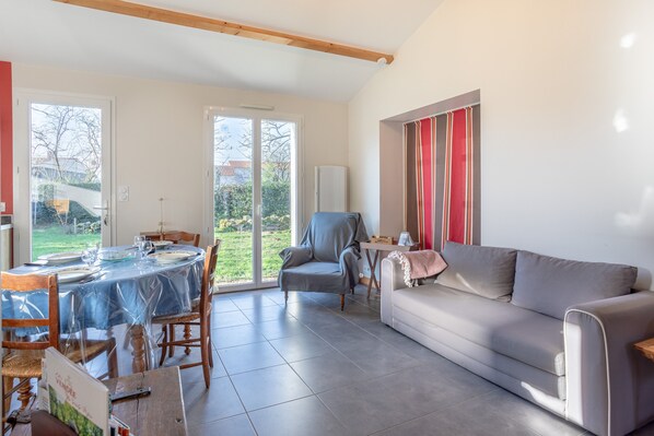 A spacious living area with a dining table, a sofa, and a chair.