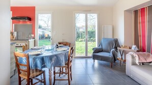 A dining area with a table set for four, a kitchen with a stove and oven, and a sliding glass door leading to a garden.