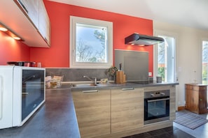 A modern kitchen with a large window, a built-in oven, and a wooden cabinet.