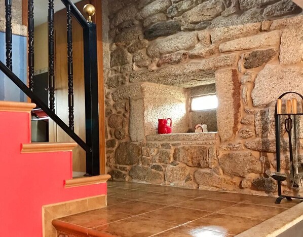 Un escalier avec un mur en pierre, une tasse rouge et une lampe noire.