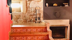A staircase with patterned tiles leading to a stone wall, a fireplace, and a shelf with decorative items. - Country House 'Fidalgo' with Mountain View, Private Terrace and Wi-Fi (Vimianzo)