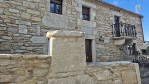 A stone building with a balcony, a door, and a window. - Country House 'Fidalgo' with Mountain View, Private Terrace and Wi-Fi (Vimianzo)