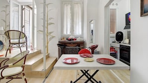 A dining area with a table set for four, a staircase, and a kitchen area with an oven.