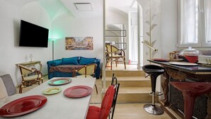 A dining area with a table set for four, a sofa, and a bar area with stools.