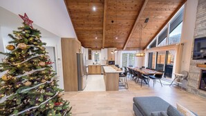Una cocina moderna con armarios de madera, una isla central y un comedor con una mesa grande y sillas.