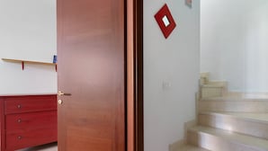 Eine Holztür, ein roter Nachttisch und eine Treppe mit einer roten, quadratischen Wandverziierung.
