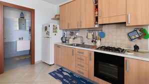 Eine Küche mit Holzschränken, einem Kühlschrank, einem Herd und verschiedenen Küchengeräten.