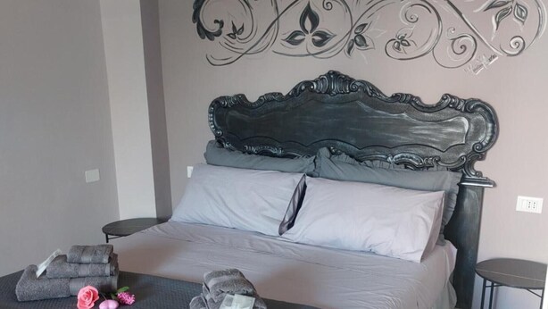 A bedroom with a bed, pillows, a decorative wall piece, a bedside table, and a small table. - Apartment 'Fede's Home' with Private Terrace, Wi-Fi and Air Conditioning (Fiumicino)
