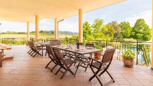 An outdoor patio with a table set for dining, surrounded by chairs, and overlooking a scenic landscape with a pool. - Amazing home in Gualdo Cattaneo (PG) (Gualdo Cattaneo (PG))