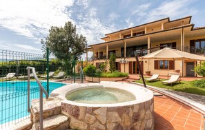 A pool area with a hot tub, lounge chairs, and a building with balconies. - Cozy home in Gualdo Cattaneo (PG) (Gualdo Cattaneo (PG))