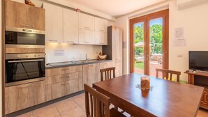 A modern kitchen with wooden cabinets, a built-in oven, and a dining area with a wooden table and chairs. - Amazing home in Gualdo Cattaneo (PG) (Gualdo Cattaneo (PG))
