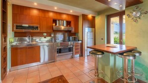 A modern kitchen with stainless steel appliances, wooden cabinets, and a bar area with stools. - Amazing home in Gualdo Cattaneo (PG) (Gualdo Cattaneo (PG))