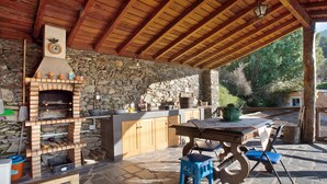 Une cheminée en pierre avec une horloge, une table en bois avec des chaises et un mur en pierre.