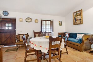 Ein Essbereich mit einem runden Tisch, Holzstühlen, einer Couch und einem Gemälde an der Wand.