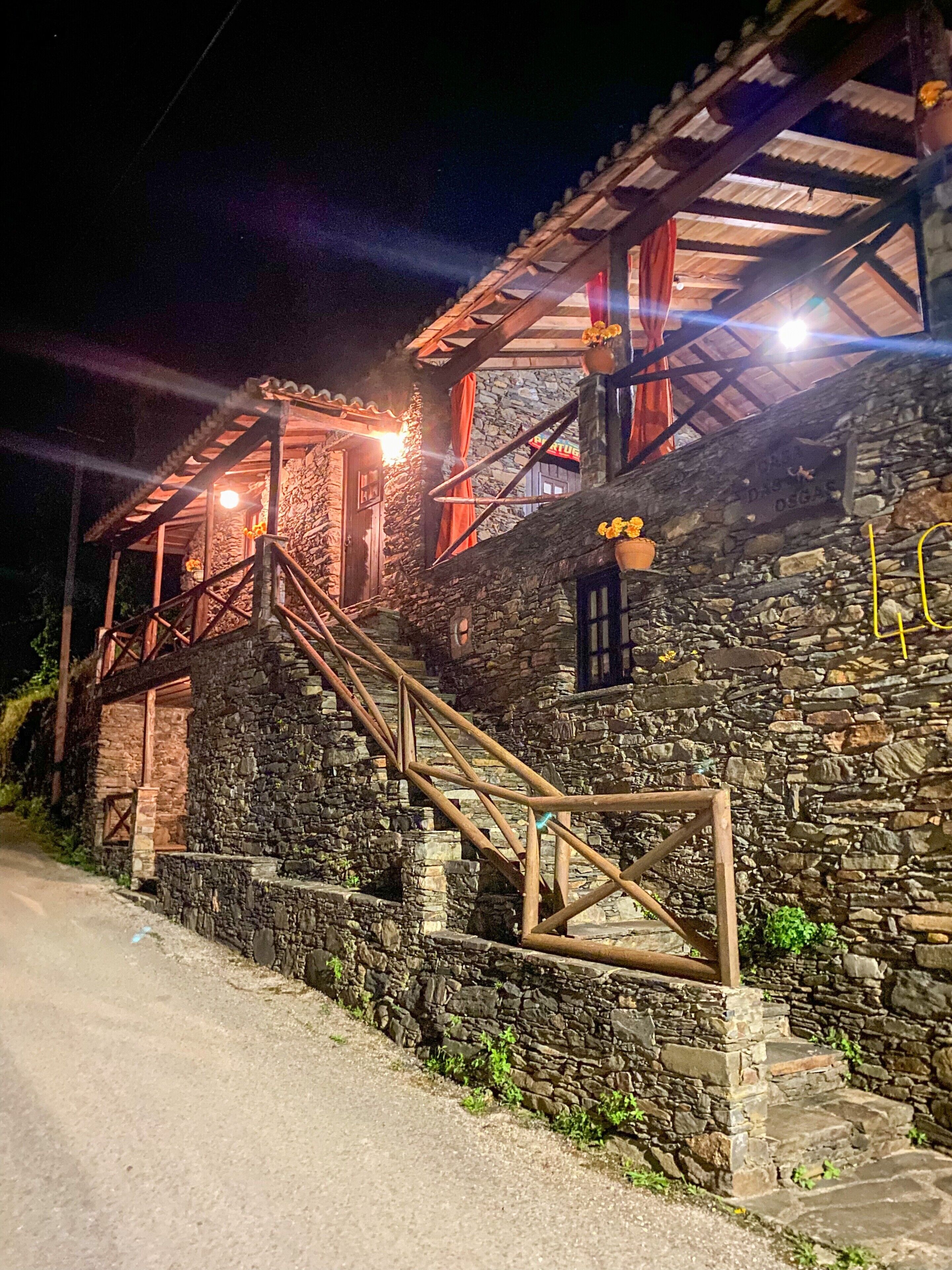 A stone building with a wooden staircase leading to a porch.