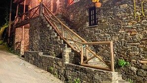 Un bâtiment en pierre avec un escalier en bois menant à un porche.