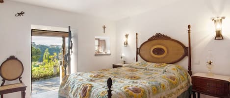 Una camera da letto con un letto grande, una testiera in legno, un comodino, una lampada da parete e una sedia, oltre a una finestra con vista.
