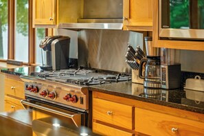 A kitchen with a stainless steel stove, wooden cabinets, and a coffee maker. - Woodsy Waterfront Retreat on Gorgeous Balsam Lake (Balsam Lake)