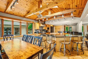 A spacious kitchen with wooden cabinets, a central island, and a dining area with a large wooden table and chairs.