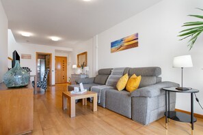 Ein modernes Wohnzimmer mit grauem Sofa, einem Holztisch und einem kleinen Beistelltisch.