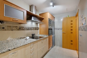Eine Küche mit Granit Arbeitsplatten, Edelstahlgeräten, Holzschränken und einer gefliesten Spritzschutzwand.