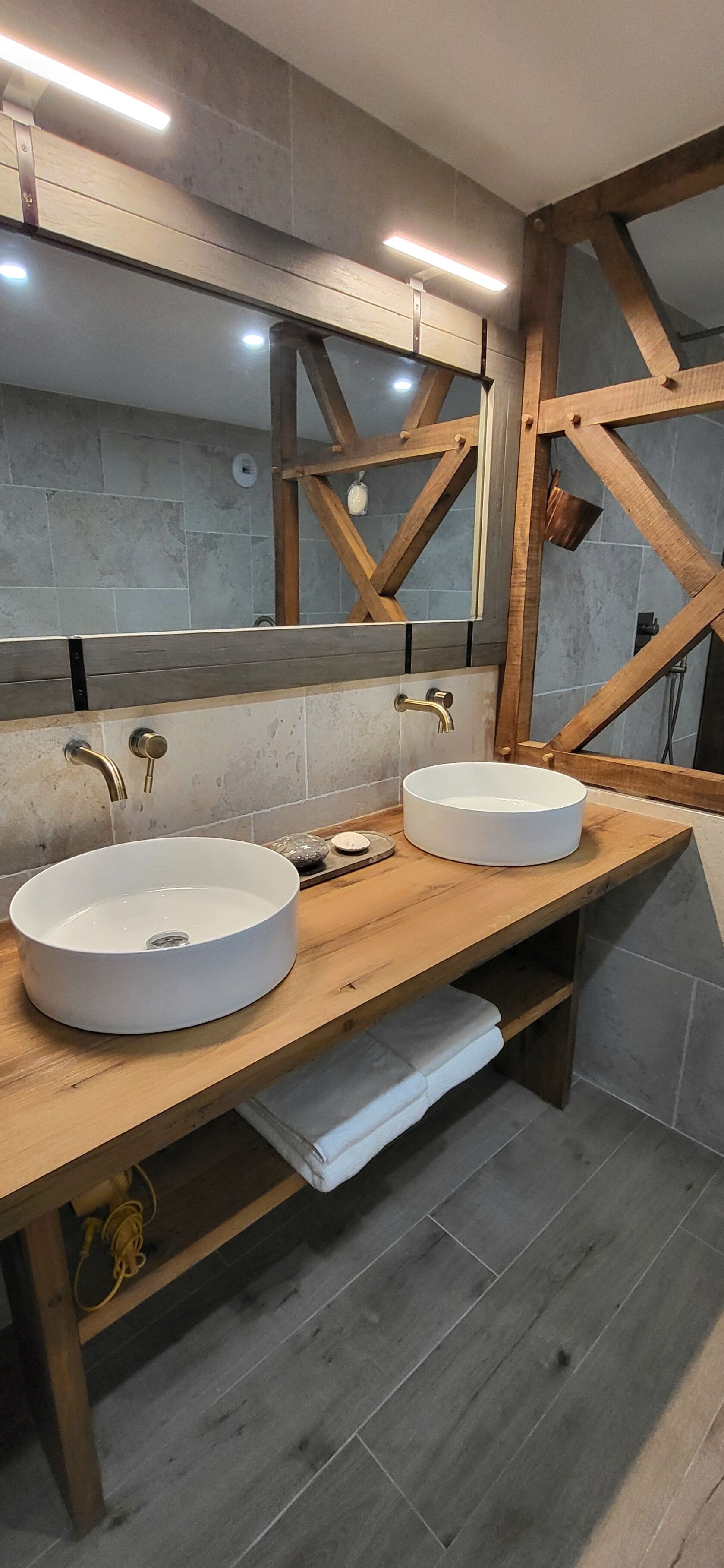 A bathroom with two white sinks, wooden vanity, and a large mirror.
